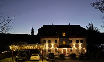 A house in the dark, illuminated with festive lights. The sky is clear and it is twilight.