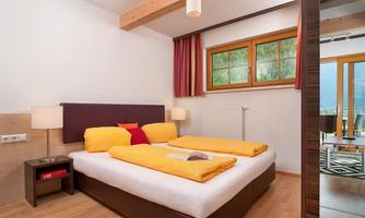 A cozy bedroom with a large bed and colorful blankets.  
Large windows let in plenty of daylight and create an inviting atmosphere.