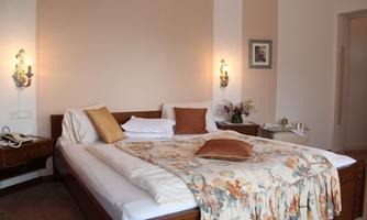 A cozy bedroom with a large bed and fluffy pillows. The soft lighting and decorative elements create a relaxed atmosphere.