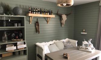 A cozy room with a green wardrobe and a wooden bench. Barrels and a cow head hang on the wall, giving the room a rustic charm.