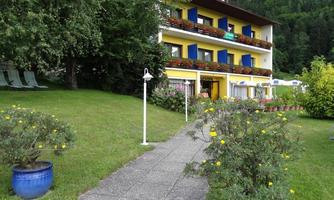 A charming building with colorful windows, surrounded by green grass and flowers. The path leads to an inviting front door.