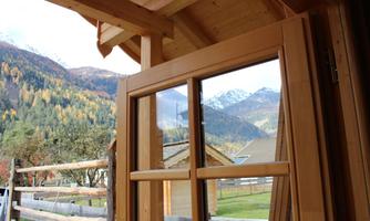 A view from a wooden door onto a picturesque mountain landscape. The colorful trees and snow-covered peaks create a tranquil and inspiring backdrop.