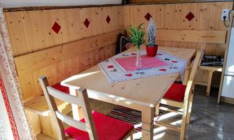 A cozy dining area with a wooden table and chairs. On the table, there is a tablecloth with a plant in a red pot.
