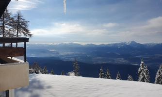 A winter landscape with snow-covered trees and mountain hills. The sky is clear and sunny, making the view especially beautiful.