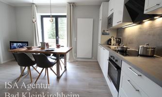 A modern, bright kitchen with a dining area and a window. The table is nicely set, and a television is visible in the background.