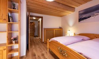 A cozy bedroom with a wooden bed and a warm wooden ceiling. The room has a beautiful wardrobe and a quiet atmosphere.