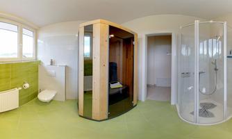 A modern bathroom with a glass shower and a sauna. The walls are tiled in light green, and large windows provide plenty of natural light.