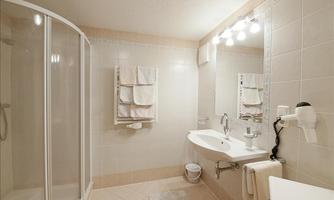 A modern bathroom with a shower, sink, and mirror. The walls are bright tiles and towels hang neatly on a towel rack.