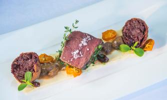 An elegant dish with tender meat, accompanied by sautéed mushrooms and fresh herbs. The appealing presentation is complemented by a light sauce.