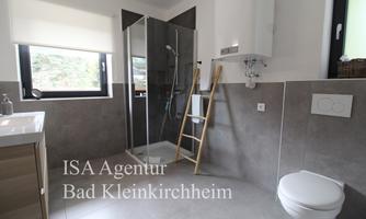 A modern bathroom with a shower, a sink, and a toilet. Bright windows provide plenty of daylight.
