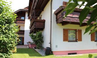 A cozy multi-story building with wooden balconies and beautiful plants. The garden is well-maintained and invites relaxation.