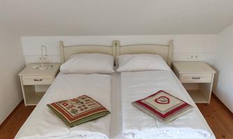 A cozy bedroom with a white double bed and two nightstands. Decorative pillows are lying on the bed.
