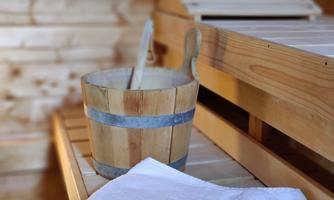 A wooden barrel with a towel in a sauna. The walls are made of wood and there is a wooden bench.