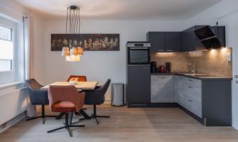 A modern kitchen with a dining area. The decor is stylish and cozy, with a bright color scheme.