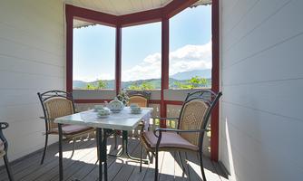 An inviting room with a table and chairs, surrounded by windows. It offers a beautiful view of the landscape outside.