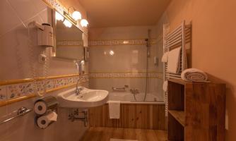A bright bathroom with a bathtub, shower, and a sink. Wooden and tile accents create a cozy atmosphere.