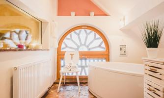 A modern bathroom with a round bathtub and a spacious window. The walls are decorated in soft colors, and there are green plants for decoration.
