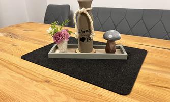 A decorative table with a wooden base. On the table are a gray vase, a small flower, and a wooden mushroom.