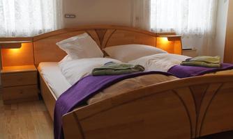 A cozy bedroom with a large double bed and soft pillows. The walls are light and there is soft lighting from the nightstands.