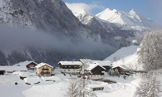 A picturesque landscape with snow-covered mountains and cozy houses. The sky is clear, and the scene radiates a tranquil winter atmosphere.