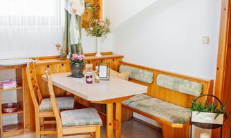 A cozy dining area with a wooden table and benches. On the table sits a plant and a small vase with flowers.