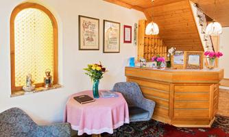 An inviting reception area with wooden decor and cozy seating. A small table decoration with fresh flowers and information on the table completes the picture.