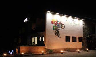 A charming restaurant with a creative mural of a tractor. The facade is illuminated by warm lighting and an inviting atmosphere at night.