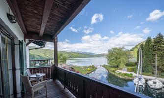 A beautiful balcony overlooking a tranquil lake and green shores. The sky is clear and sunny, perfect for relaxing moments.