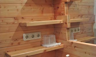 A modern bathroom with wooden walls and shelves. The sink is neatly decorated with soap and towels.