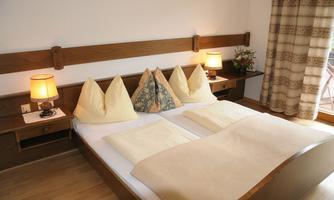 A cozy bedroom with a double bed and two nightstands. The pillows are decorative and there is soft lighting from the lamps.