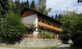 A charming house with a wooden balcony and a well-kept garden. Surrounded by trees and shrubs, it radiates a calm atmosphere.