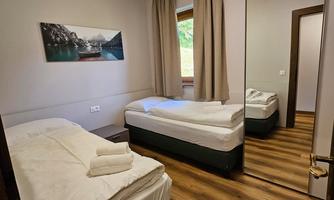 A simple room with two single beds and a large mirror. The window offers a view of nature.