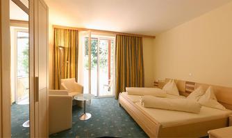 A cozy room with two single beds and modern furniture. Large windows let in plenty of light, and the space has a friendly atmosphere.