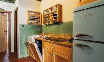 A cozy kitchen with wooden cabinets and a green tiled backsplash. A retro-style refrigerator and a dishwasher are also visible.