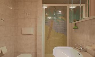 A modern bathroom with a shower, a toilet, and a sink. The walls are covered with tiles in light colors.