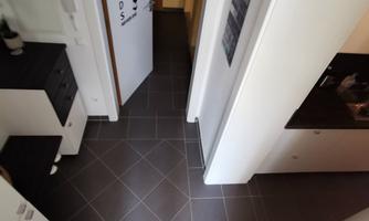 A bright hallway with modern tiles and white walls. An artistic poster titled "LEGENDS" hangs on one wall.