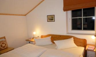 A cozy bedroom with a double bed and fresh white bed linen. The window lets in soft light and creates an inviting atmosphere.