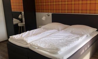 A cozy bedroom with a large double bed and modern furniture. The walls are decorated with an orange checked pattern.