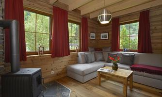 A cozy living room with wood paneling and large windows. The seating area is inviting with a table and a modern heater.