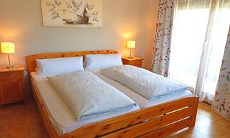 A cozy bedroom with a double bed and bright furniture. Large windows let in plenty of daylight.