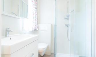A modern bathroom with a shower and a sink. A bright yellow bath mat adds a cheerful accent.