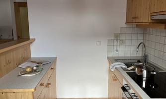 A modern kitchen with wooden cabinets and a bright tile surface. Some ingredients are on the countertop and a pot is ready.