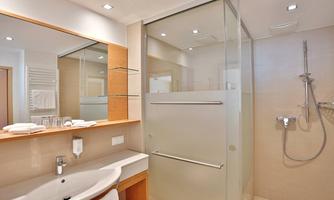 A modern bathroom with a glass shower cabin and a stylish sink. Bright walls and a minimalist decor create a pleasant atmosphere.