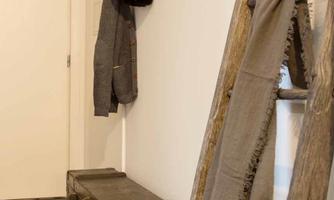 A stylish hallway with a wooden shelf and a hook for coats. Boots and a blanket are on the floor.