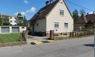 A cozy single-family home on a quiet street.  
In the foreground, there is a garden and garages.