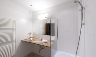 A modern bathroom with a glass shower cubicle and an elegant sink. The walls are in light, neutral colors.