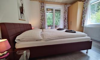 A cozy bedroom with a large bed and a wardrobe. The room has large windows that provide plenty of daylight.