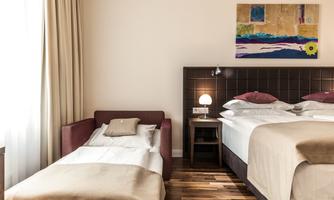 A beautiful room with two beds and a pull-out bed. The walls are light, and there is a decorative painting.