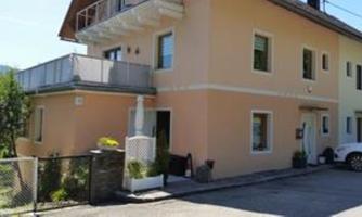 A modern, bright house with a balcony and a well-maintained front garden. Parking is available at the house.