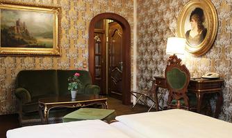 An elegant hotel room with vintage decor. The room features a cozy couch, a table, and a picture on the wall.